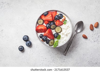Cottage cheese with strawberries, nuts and blueberries in a gray bowl for breakfast, top view. Summer recipe.