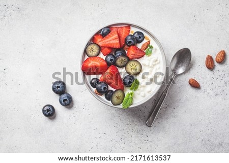Cottage cheese with strawberries, nuts and blueberries in a gray bowl for breakfast, top view. Summer recipe.