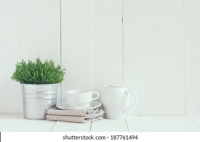 Cottage Life, Country Kitchen Decoration: A House Plant In A Metal Pot, Kitchen Pottery, Utensils And Napkins On White Painted Board. Cozy Home Country Life Background Is.