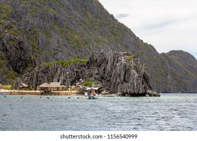 Cottages and boat between karst rocks in philippine sea