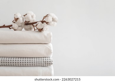 Cotton branch with pile of neatly folded bed sheets, blankets and towels. Production of natural textile fibers. Manufacture. Organic product. - Shutterstock ID 2263027215