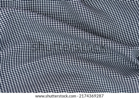 Cotton fabric with black and white houndstooth pattern lying in folds.