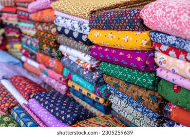 Cotton fabrics. Natural multi-colored fabrics with various patterns and patterns are in large piles in fabric store. Different textures of fabrics. Textile production and sale. Natural bright dyes. - Powered by Shutterstock