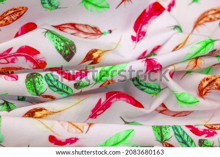 Cotton, jersey. print of bird feather red brown green on white background. Cotton jersey is usually a thin fabric with a sheer front and back.