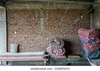 Cotton Mattress Rolled Up On A Cot In Front Of A Brick Wall