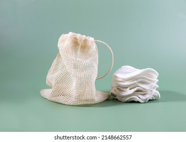 Cotton reusable make-up remover pads in a cloth bag on a green background. The concept of ecology and conscious consumption. Reusable cotton pads. - Shutterstock ID 2148662557
