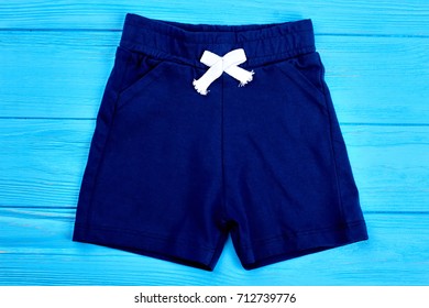 Cotton Shorts For Toddler Boy. Textile Blue Short Pants For Infant Boy On Wooden Background. Childrens Apparel On Sale.