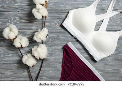 Cotton striped panties and white bra. Women's lingerie on the wooden background. Top view shot of fashionable women's underwear. Natural soft fabric