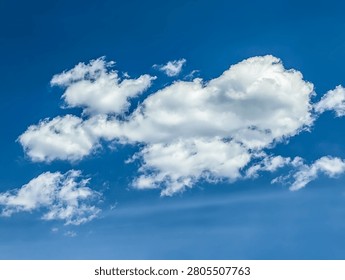 Cotton structure of several clouds moves freely across the blue sky. The gentle movement of an atmospheric front. A majestic swirling spectacle on cold cool background.
