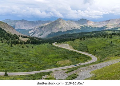 Cottonwood Pass - A panoramic Summer day view of a mountain road winding in a green valley at east of  the summit of Cottonwood Pass. Buena Vista - Crested Butte, Colorado, USA.