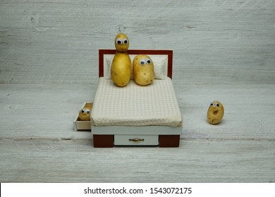 A Couch Potato Family, Showing A Double Bed With Wiggle Eye Spuds, On A Wooden Plank Display Board.