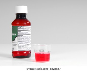 Cough Medicine Bottle And Warning Label With Poured Dose On Counter