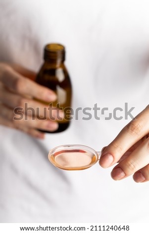 Cough syrup in a spoon. Temperature syrup. Medicine, health, virus protection.