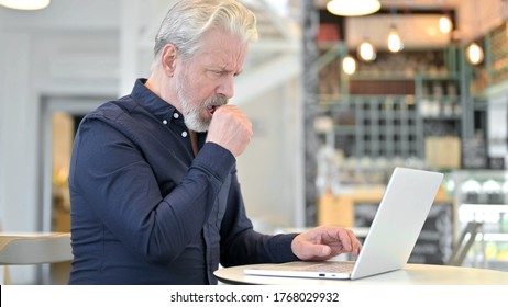 Coughing Old Man Using Laptop In Cafe