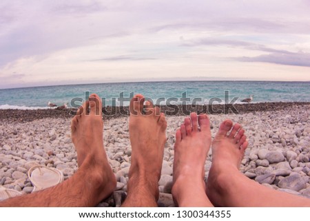 Coulpe lying on a beach - playing with feets. Gulls are walking along the azure shore. Fantastic colors over sunset