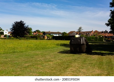 A Council Worker Riding On A Sit On Lawnmower Cutting The Grass In A Public Park On A Hot Summers Day