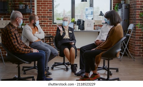 Counselor Helping People With Alcohol Addiction At Aa Meeting Therapy During Covid 19 Pandemic. Psychiatrist Talking To Multi Ethnic Group Of Patients With Face Mask At Rehab Program.