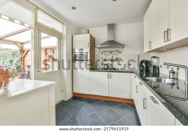 Counter with chairs dividing kitchen\
with modern furniture from dining area in contemporary\
flat