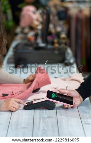 Counter with a customer paying with smartphone in a clothing shop