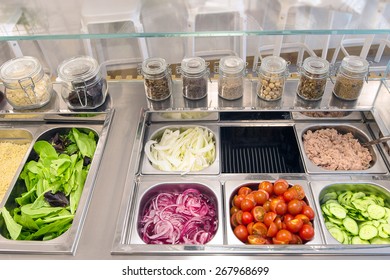 Counter with sandwich condiments and fresh organic ingredients: onions, cherry tomatoes, cucumbers, tuna fish, fennel, lettuce and various spices