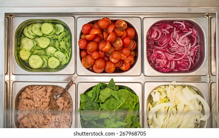 Counter With Sandwich Condiments And Fresh Organic Ingredients: Onions, Cherry Tomatoes, Cucumbers, Tuna Fish, Fennel, Lettuce And Various Spices