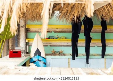 Counter of sunny surf hire shop on beach with radio, surfboard and hanging wetsuits. Local business, leisure, hobbies, sport, surfing, summer and vacations. - Powered by Shutterstock