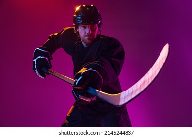 Counterattack. Professional male hockey player training in special uniform with helmet isolated on pink background in neon. Concentration. Concept of sport, action, movement, health. Copy space for ad