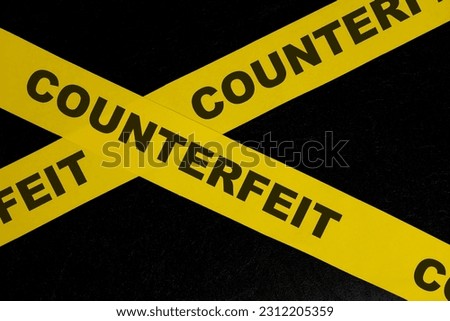 Counterfeit product and item caution and warning concept. Yellow barricade tape with word in dark black background.