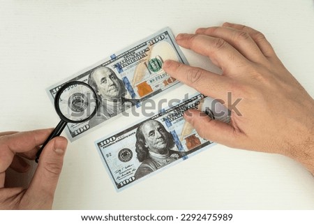 Counterfeiter forges banknotes. Fake concept. Fake money American dollars, magnifier. view money under a magnifying glass. watermark, water mark. search for counterfeit bills