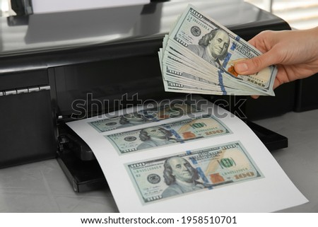 Counterfeiter printing dollar banknotes at grey table, closeup. Fake money concept