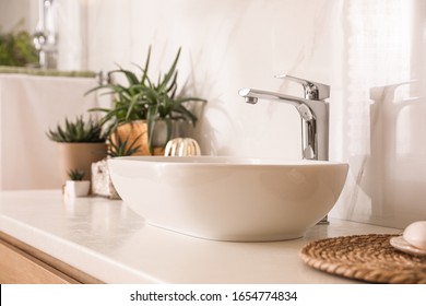 Countertop with sink and houseplants in bathroom. Interior design