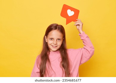 Counting clicks on viral content. Communication through comments on blogs. Joyful little girl wearing pink sweatshirt holding blogger heart like icon over her head isolated over yellow background