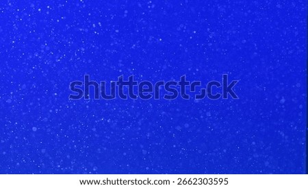 Countless tiny air bubbles suspended in water, set against a deep blue background, creating a light, ethereal, and abstract texture.