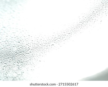 Countless tiny translucent water droplets create a dense, repetitive pattern of condensation on a smooth, reflective surface.