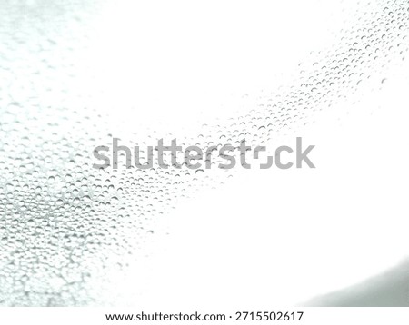 Countless tiny translucent water droplets create a dense, repetitive pattern of condensation on a smooth, reflective surface.