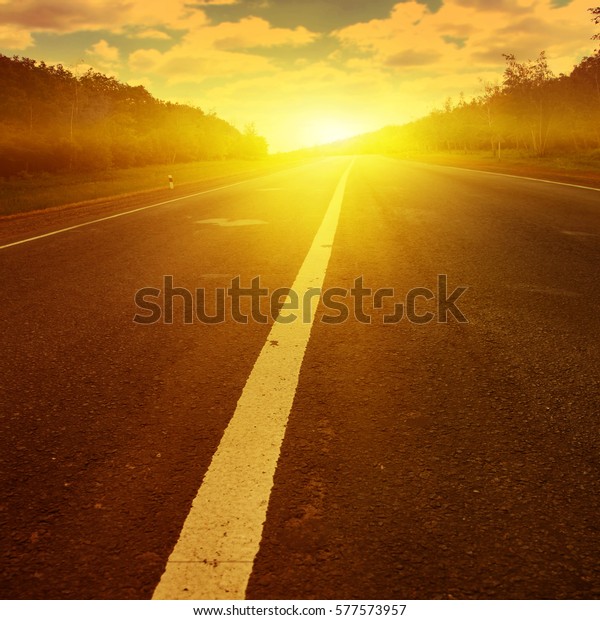 Country asphalt road at\
sunset.