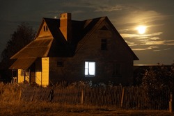 Country Brick Home With Window Light Under Full Moon At Summer Night