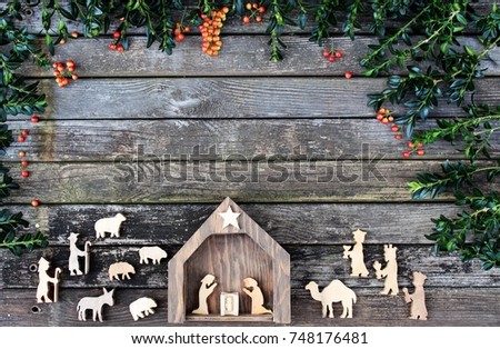 country christmas nativity on rustic wood background with greenery