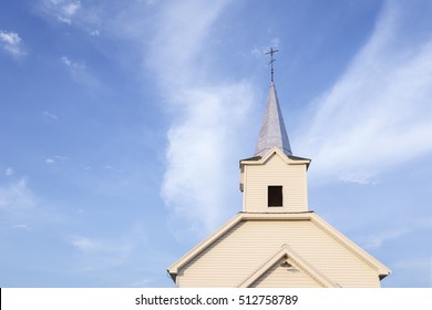 country church steeple against blue sky and white clouds
