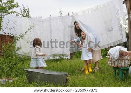 Country Comforts: A mother and her tiny tots bring laughter and love to the mundane chore of laundry, embodying the simplicity of rural living.