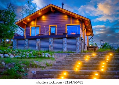 Country cottage. Steps Lead to country house. Modern suburban sunset house. Country hotel on background of evening sky. Wooden cottage in Scandinavian style. Concept of renting holiday cottages