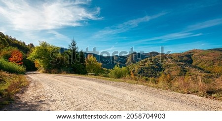 country gravel road in apuseni mountains, cluj country, romania. sunny autumn scenery in morning light. blue sky with clouds