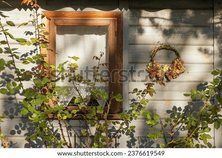Country house decorated with autumn wreath, rose bushes around the window