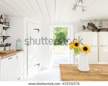 country house kitchen interior with sunflowers in a vase and a open door out to the garden