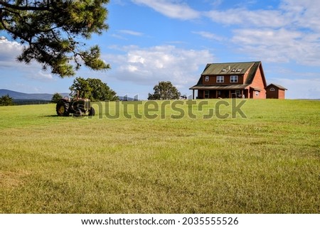 A country house on a hill with a old tractor sitting in front of it- A vintage tractor sitting in an open field on a country farm- a ranch with a old tractor sitting in the pasture- Old farm tractor 