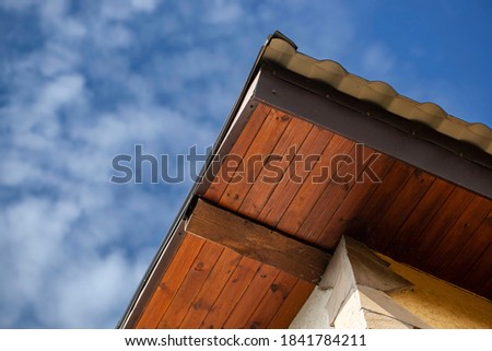 country house. The walls of the cottage whose facade is plastered with decorative plaster " bark beetle" . The view from the bottom up. Roof architecture detail with triangle shape