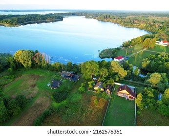 Country Houses At River In Countryside, Aerial View. Building A Home In The Country. Village With Wooden House. Suburban House In Rural On Sunset. Rural Building And Farmhouse At Lake In Countryside. 