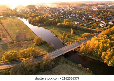 Country Houses At River In Countryside, Aerial View. Building A Home In The Country. Village With Wooden House. Suburban House In Rural On Sunset. Rural Building And Farmhouse At Lake In Countryside. 