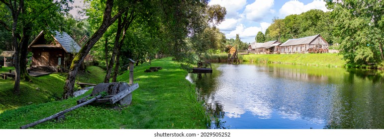 Country Landscape. A picturesque pond in the village. Old buildings, shady forest and a small lake. Village view. Farm