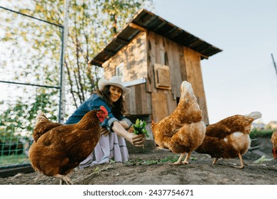 Country life, city woman feeding chickens with fresh grass. Contented middle-aged city woman enjoying country life and smiling while feeding a flock of chickens during her country holiday - Powered by Shutterstock